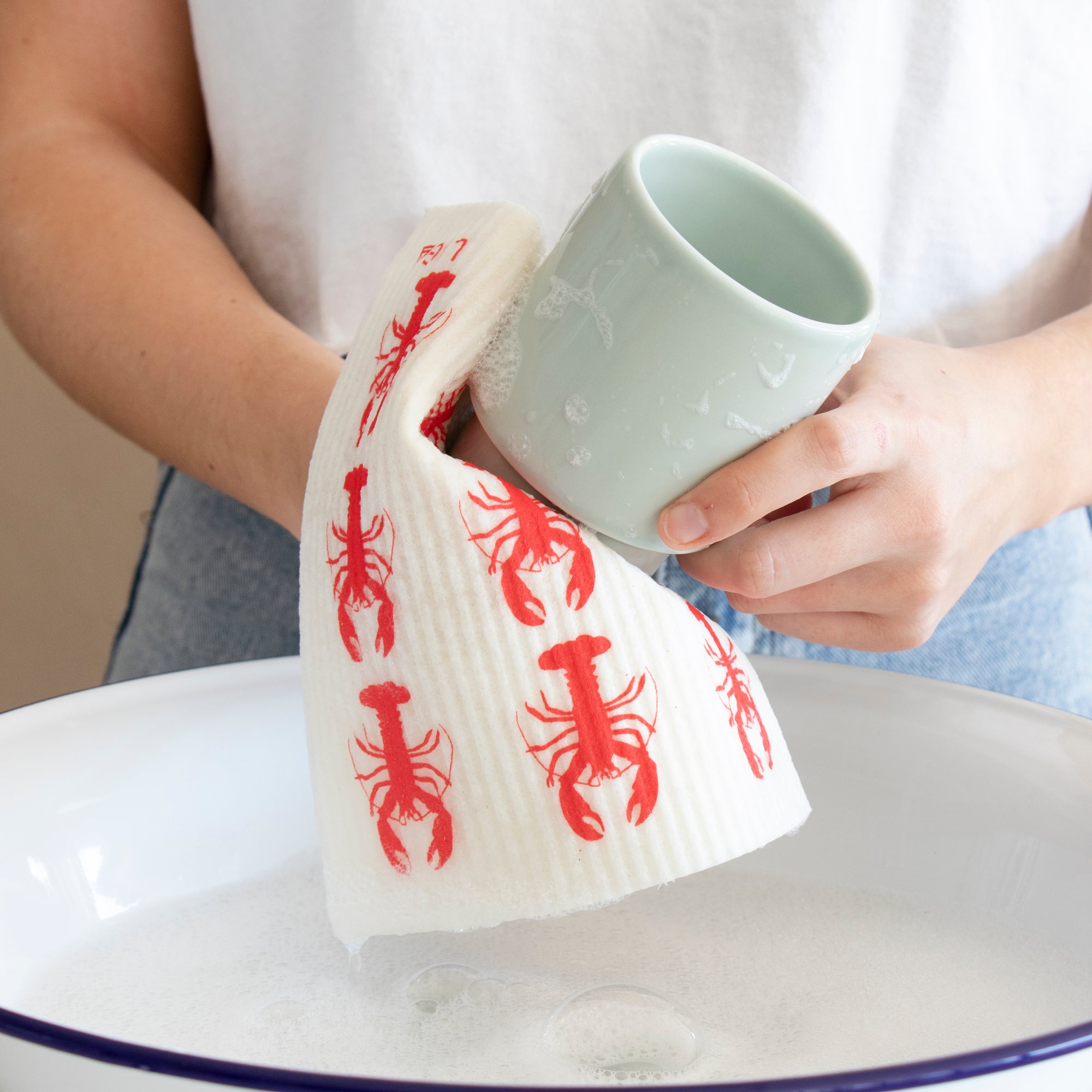 Compostable eco friendly dishcloth in use with a unique red lobster design